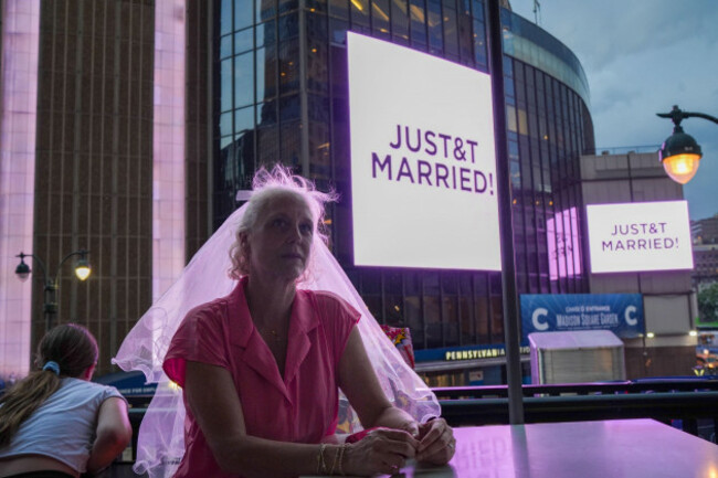 a-taylor-swift-fan-wearing-a-wedding-veil-sits-at-a-restaurant-next-to-madison-square-garden-where-a-justt-married-sign-is-displayed-during-a-wedding-between-singer-taylor-swift-and-national-footba