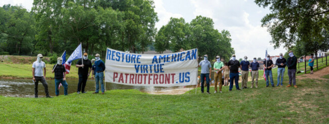 prattville-alabama-usa-june-24-2023-members-of-patriot-front-a-white-nationalist-neo-fascist-hate-group-cover-their-faces-while-holding-a-banne