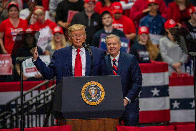 senator-lindsey-graham-smiles-behind-president-trump-at-the-rally-in-the-bojangles-coliseum