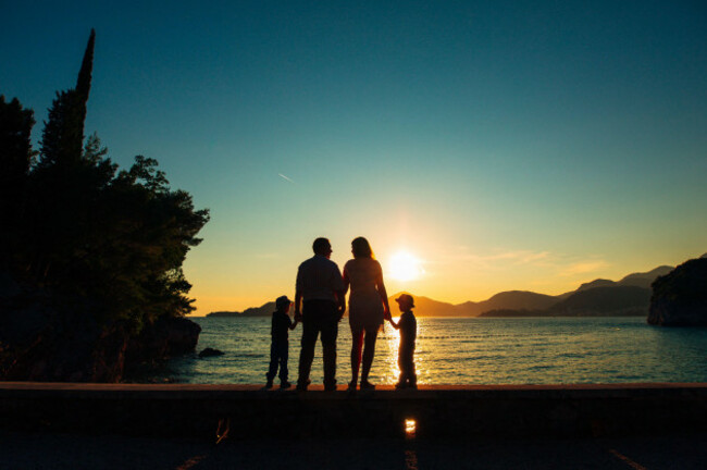 silhouette-of-parents-and-two-children-at-sea-at-sunset-montene