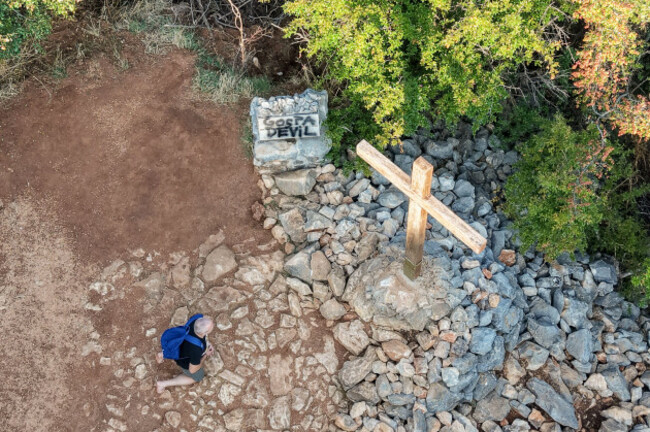 an-aerial-view-of-a-pilgrim-praying-next-to-a-vandalized-monument-bearing-the-words-gospa-devil-meaning-virgin-mary-devil-and-a-cross-on-apparition-hill-in-medjugorje-bosnia-tuesday-july-28