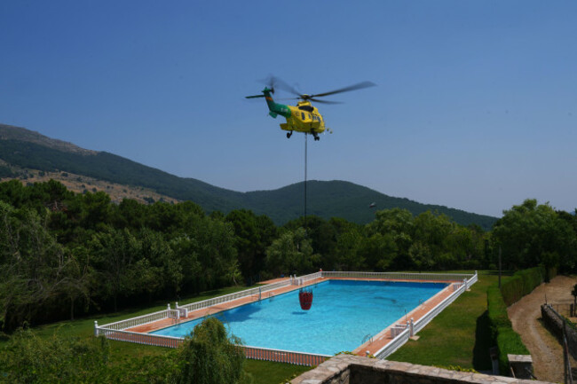 a-helicopter-scoops-water-from-a-swimming-pool-to-drop-on-a-wildfire-that-continues-to-spread-near-casillas-avila-province-spain-tuesday-july-28-2026-ap-photomanu-fernandez