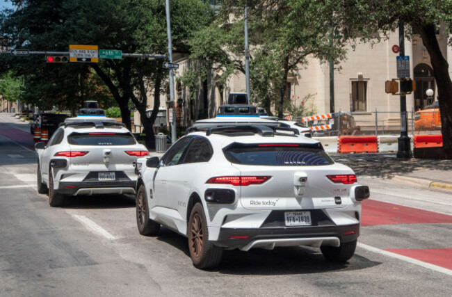 two-waymo-self-driving-cars-head-north-on-lavaca-st-in-downtown-austin-on-a-hot-summer-day-july-23-2026-waymo-operates-more-than-300-autonomous-taxis-in-a-130-square-mile-area-of-austin-making-thou