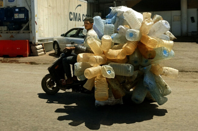 beirut-lebanon-3rd-aug-2026-a-plastic-collector-drives-his-motorcycle-loaded-with-plastic-gallons-collected-from-garbage-in-a-beirut-street-lebanons-severe-economic-crisis-has-fueled-an-informal