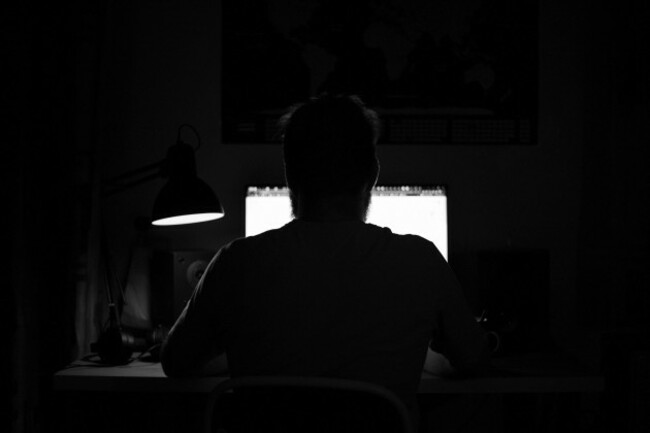 a-man-sits-at-a-computer-in-a-room-at-a-table-at-nigh-programming-black-and-white