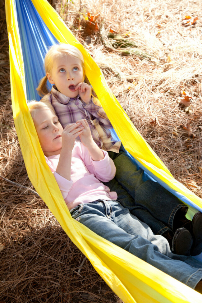 twin-sisters-are-sitting-in-a-hammock