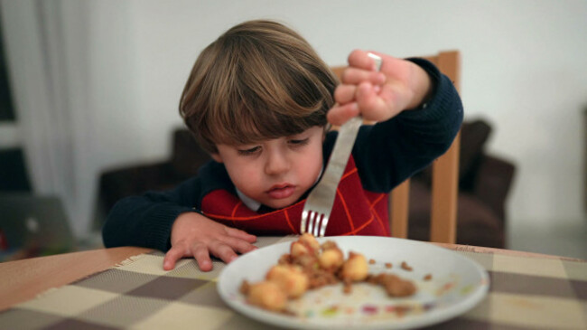 happy-small-child-eats-food-by-himself-with-fork-one-little-boy-eating-dinner-wearing-sweater-during-winter-season