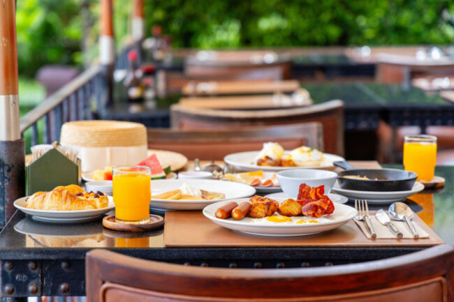 gourmet-breakfast-spread-with-eggs-bacon-sausages-and-orange-juice-served-on-a-wooden-table-at-an-outdoor-luxury-resort-terrace-morning-dining-exp