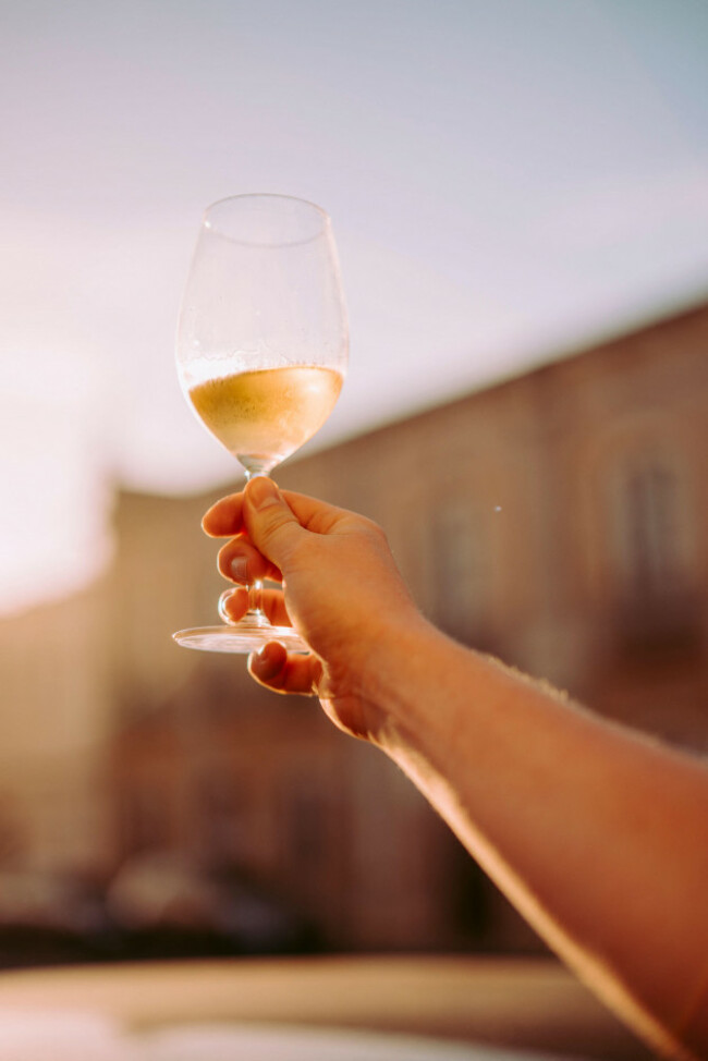 hand-of-man-sitting-in-the-outdoor-restaurant-with-a-glass-of-white-wine-up-portugal