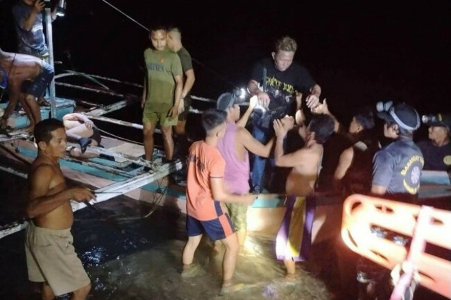in-this-image-provided-by-the-philippine-coast-guard-a-survivor-is-assisted-as-he-alights-from-a-small-boat-after-being-rescued-from-a-burning-ferry-off-palawan-province-philippines-on-wednesday-sep