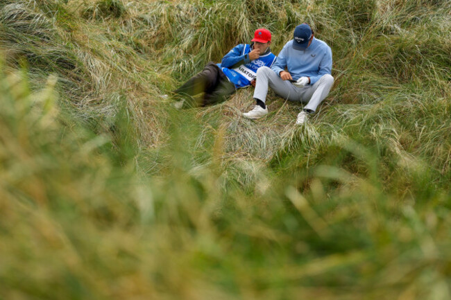 renato-paratore-waits-in-the-grass-on-the-fourth-tee-box-for-the-fairway-to-clear-with-caddie-charles-dubois