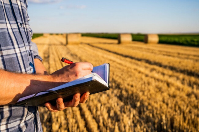 farmer-writing-notes-and-examining-straw-after-successful-harvesting