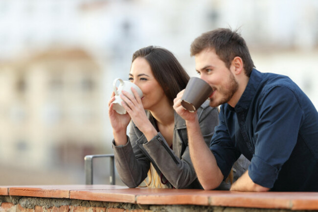 happy-couple-drinking-coffee-contemplating-views-outdoors-in-a-town-outskirts