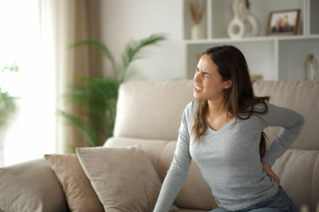 woman-suffering-back-ache-sitting-on-uncomfortable-couch-at-home
