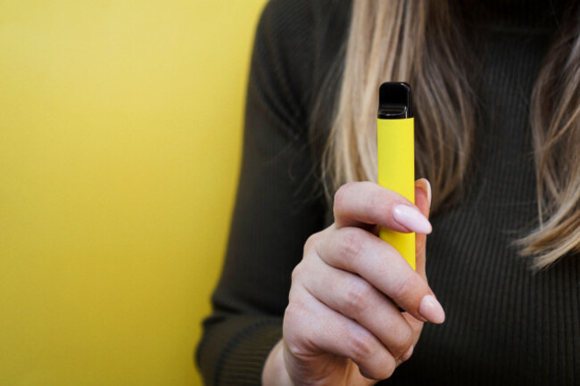 yellow-disposable-electronic-cigarette-in-female-hand-bright-yellow-background