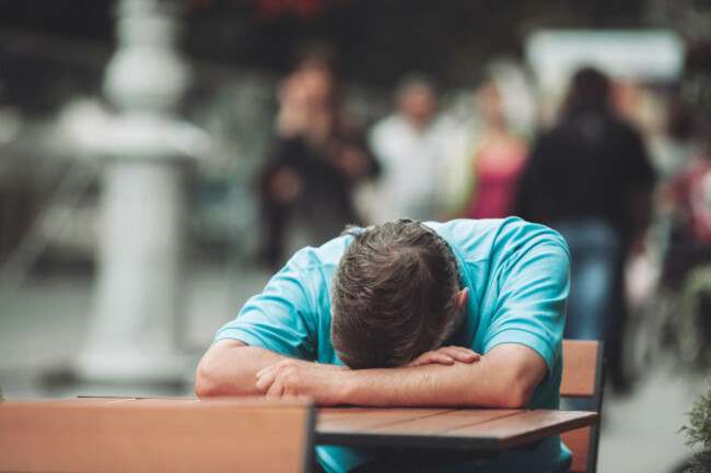 a-languishing-man-sleeps-outdoors-on-a-bench-or-table