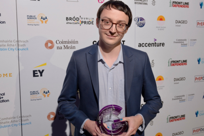 Conor wearing a suit holding a glass trophy.