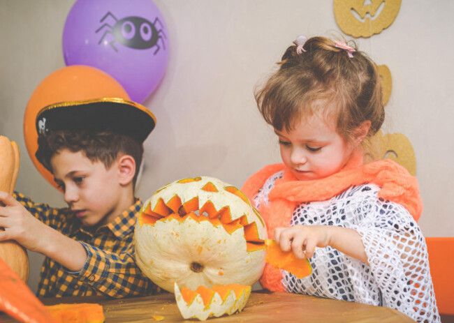 children-wearing-halloween-costumes-carving-holiday-pumpkins-for-home-decoration